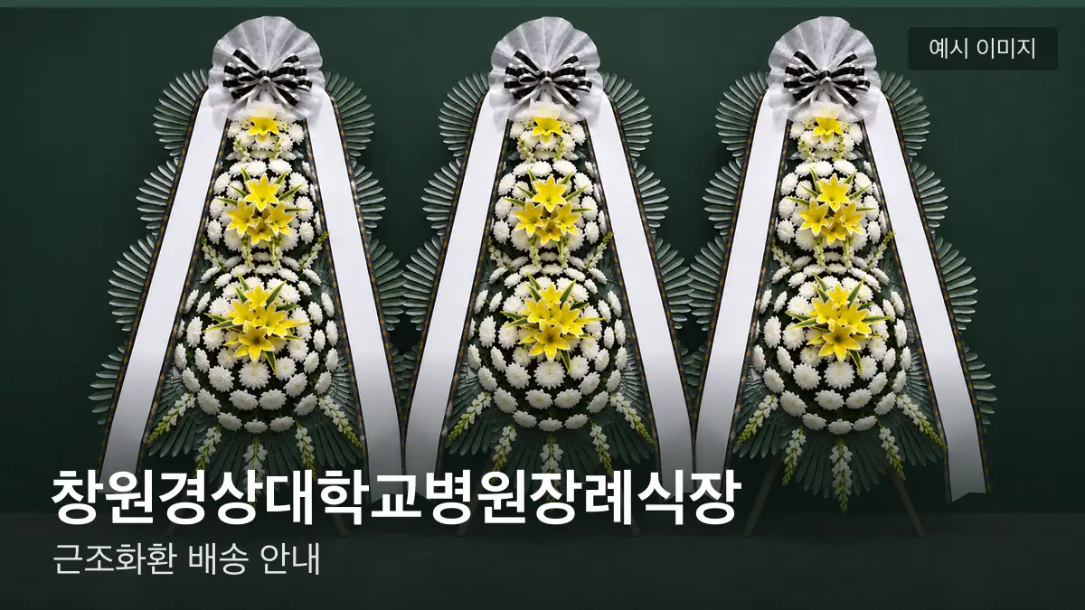 창원경상대학교병원장례식장 근조화환 예시 이미지 — 흰 국화 3단 근조화환이 벽을 따라 나란히 놓인 모습