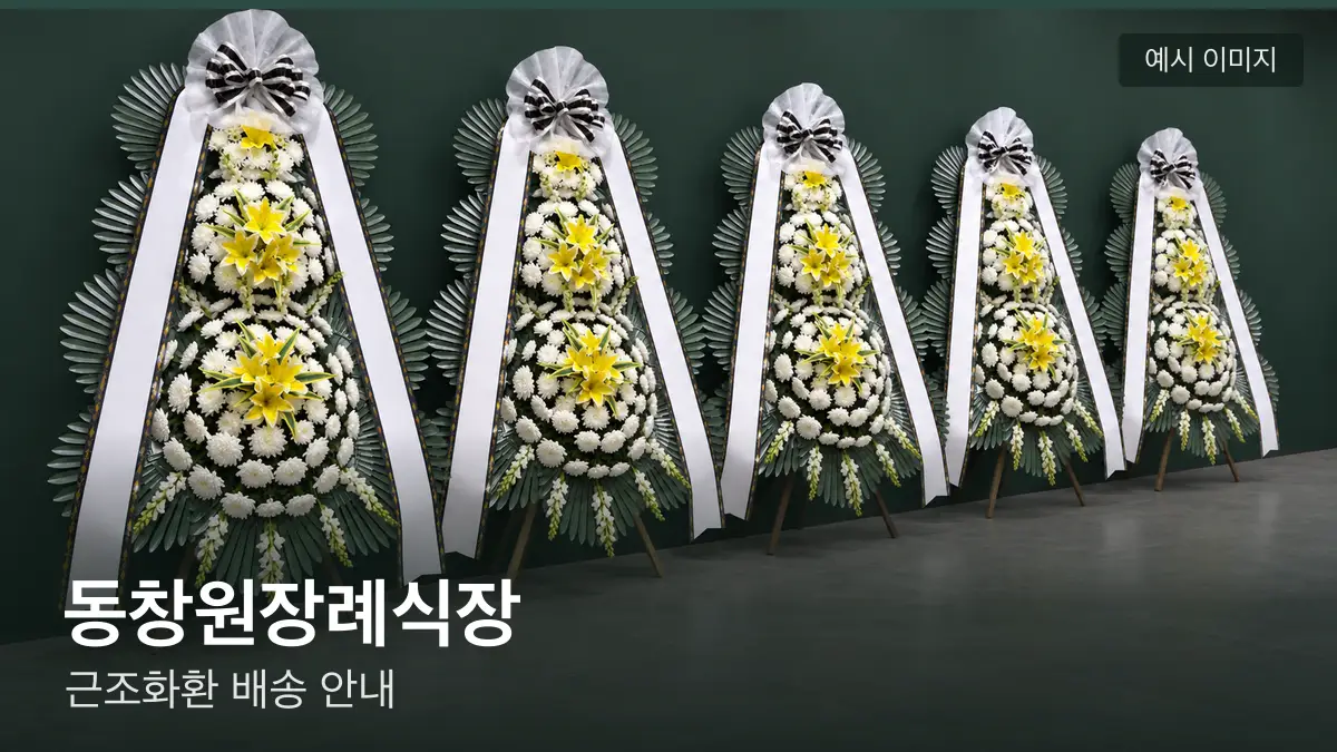 동창원장례식장 근조화환 예시 이미지 — 흰 국화 3단 근조화환이 벽을 따라 나란히 놓인 모습