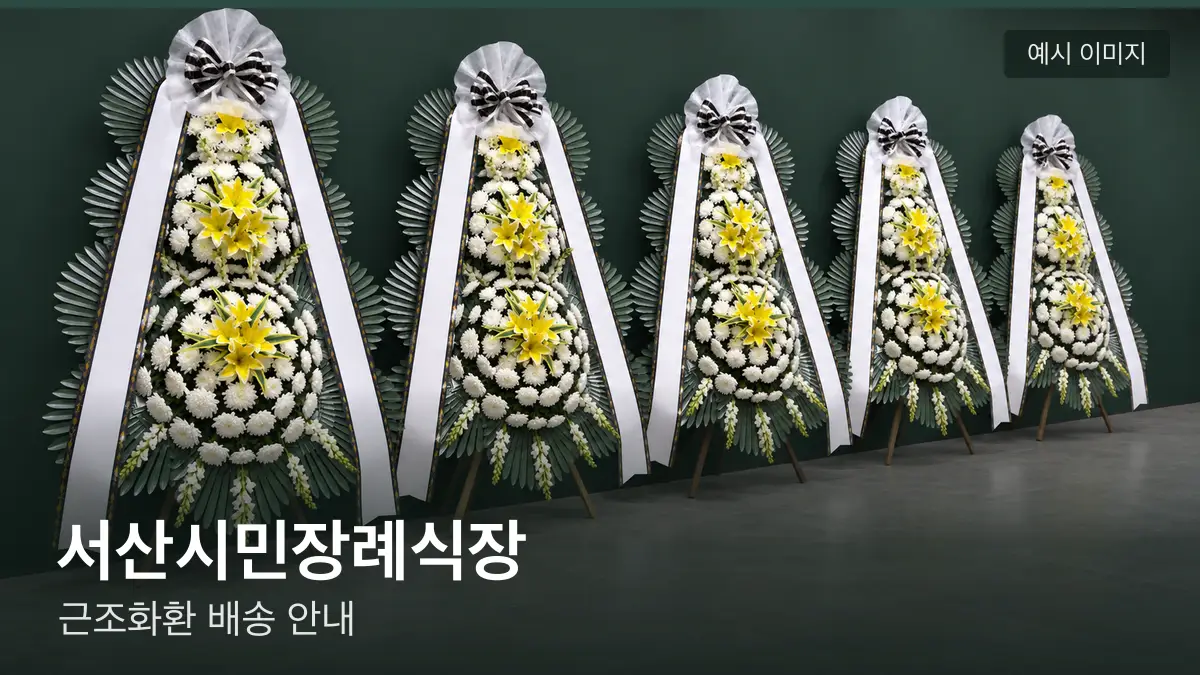 서산시민장례식장 근조화환 예시 이미지 — 흰 국화 3단 근조화환이 벽을 따라 나란히 놓인 모습